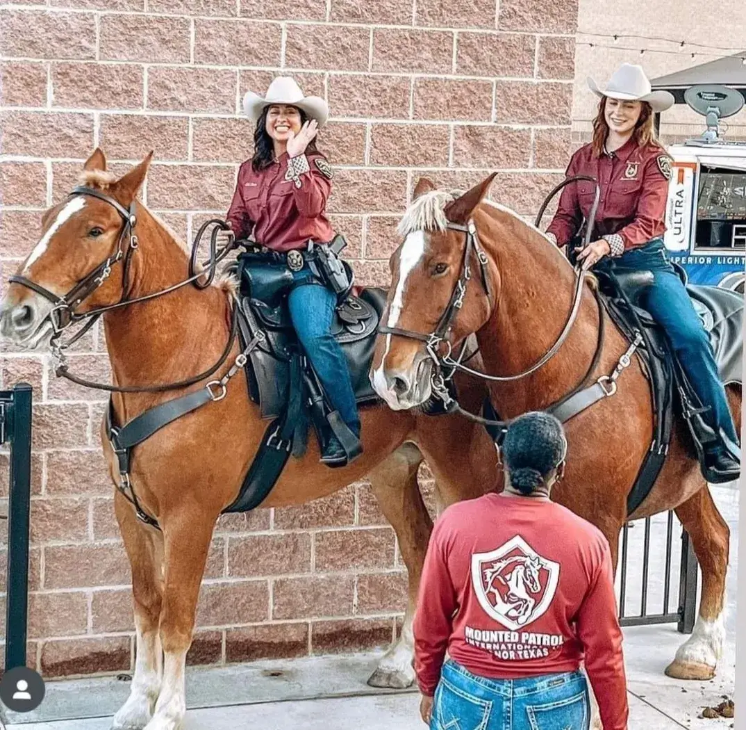 Mounted police officers on horseback, smiling.