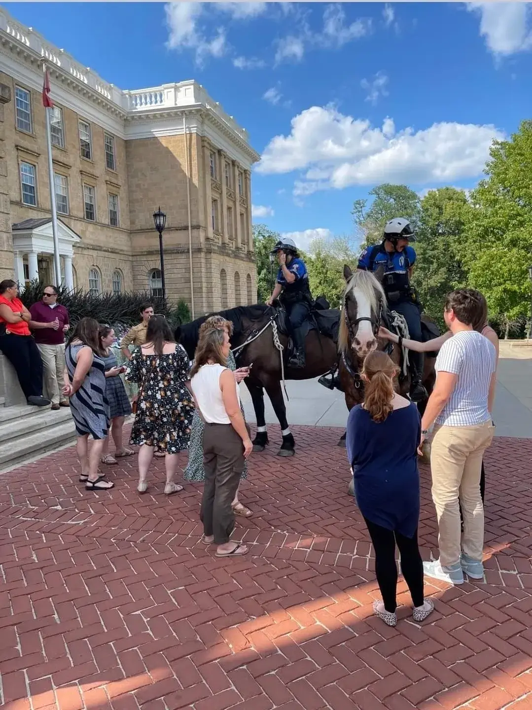People gathering around mounted police officers.