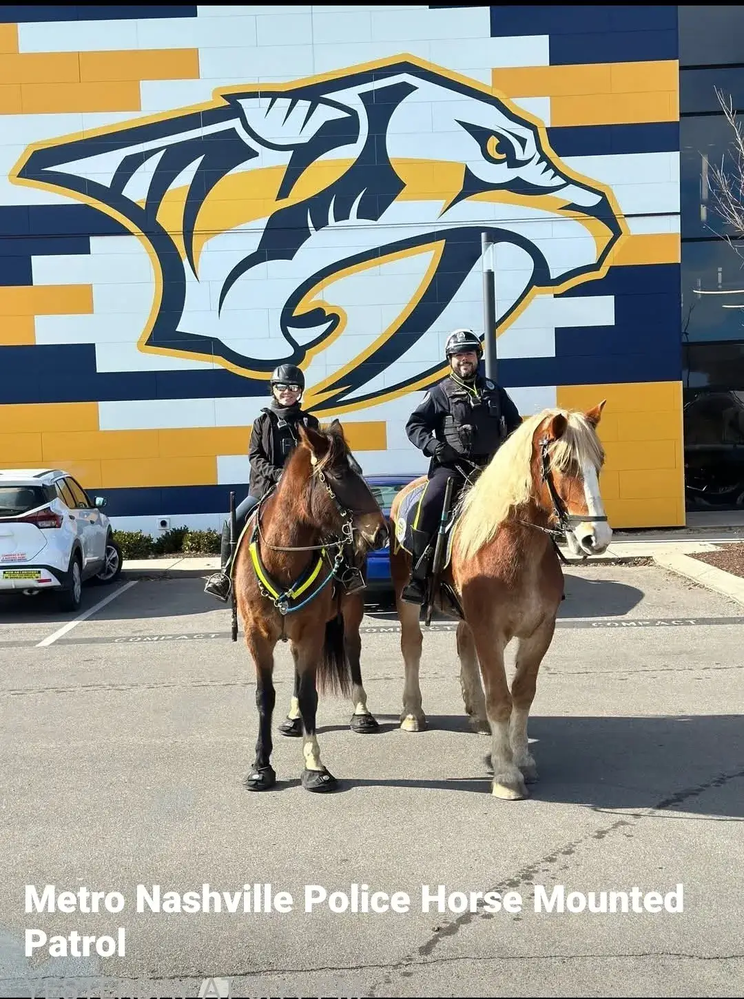 Mounted police officers in front of mural.