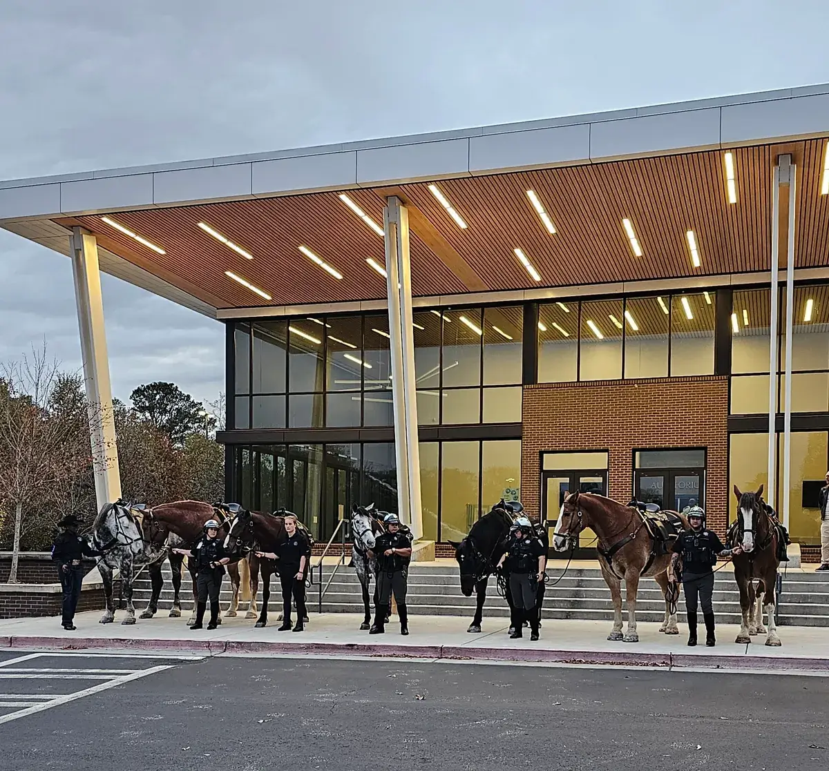 Police officers with horses in front of building.