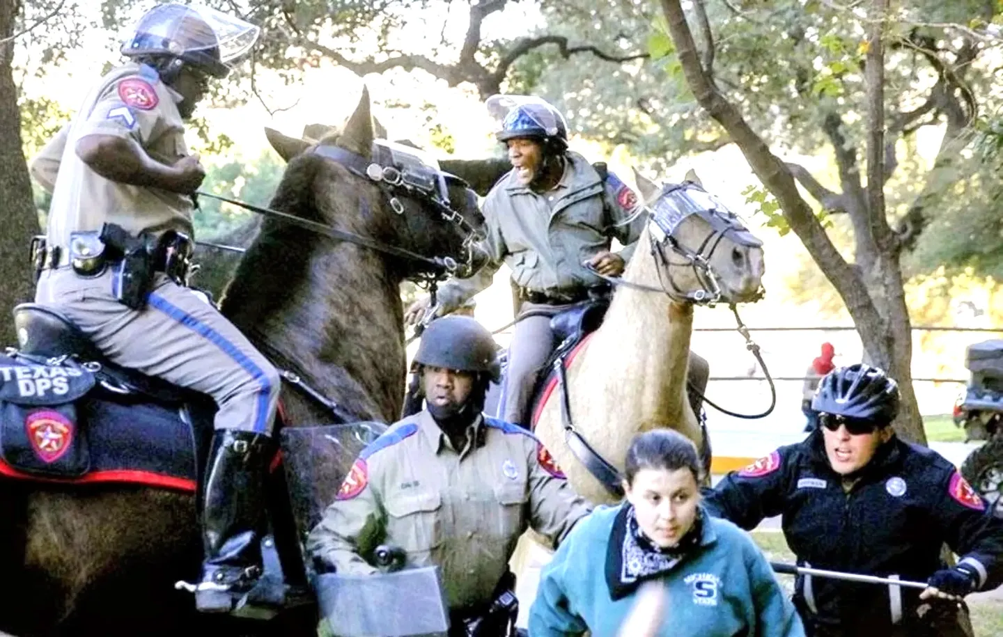 Mounted police officers in a wooded area during an operation.