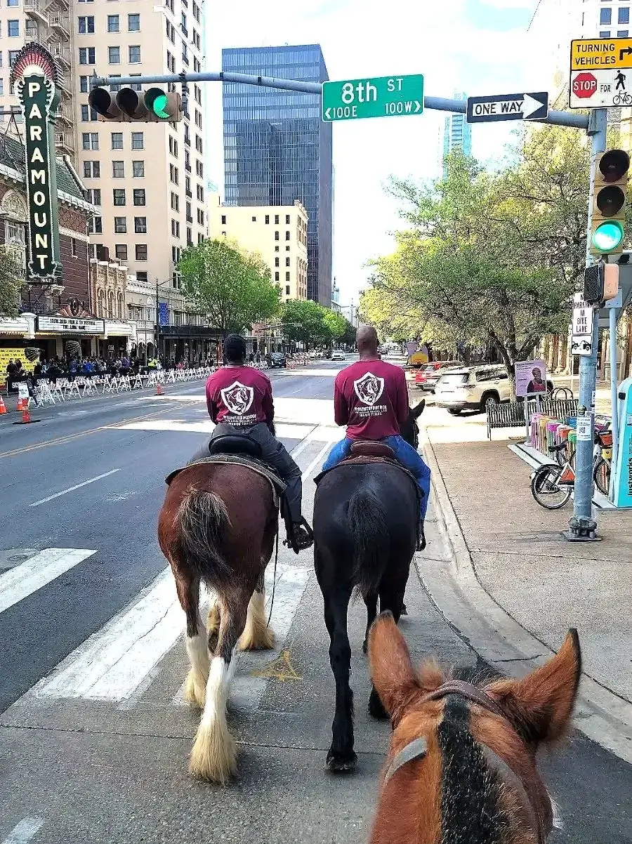 Three riders on horseback in an urban street setting.